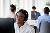 Mid adult woman using headset while sitting in office\n