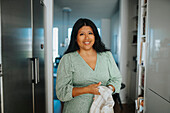 Porträt einer lächelnden Frau bei der Hausarbeit in der Küche