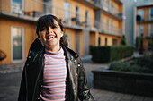 Happy smiling girl standing in courtyard of residential neighborhood\n