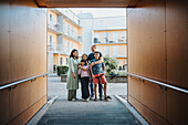 Portrait of family standing in courtyard of residential neighborhood\n