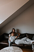 Weibliches Paar entspannt zusammen auf dem Sofa und schaut auf das Handy
