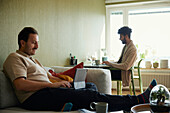 Homosexual couple relaxing in living room\n