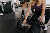 Frau packt Ausrüstung nach dem Training im Fitnessstudio