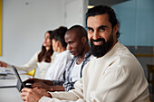 Smiling man sitting during business meeting and looking at camera\n