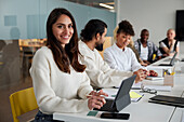 Smiling woman sitting during business meeting and looking at camera\n