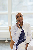 Female doctor looking away and talking via cell phone\n