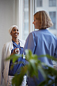 Female doctors standing and talking at hospital corridor\n