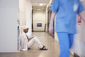 Female doctor sitting on hospital corridor floor\n