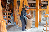 Frau in Mühle hält Sack mit Mehl in der Hand