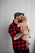 Father holding and kissing baby\n