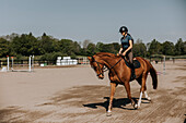 Woman horse riding on paddock at sunny day\n