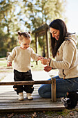 Mutter schaut Tochter beim Spielen auf dem Spielplatz zu