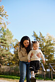 Mother helping daughter to keep balance at playground\n