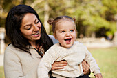 Mother sitting with laughing girl on her lap\n