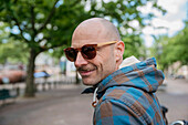 Portrait of bald man wearing sunglasses and hooded shirt\n