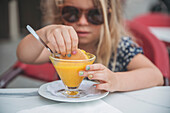 Girl eating dessert in outdoor cafe\n
