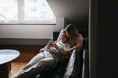 Homosexual couple sitting on sofa and using cell phone\n