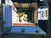 Aerial vie of courtyard surrounded by block of flats, solar panels on roof\n