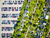 Luftaufnahme von geparkten Autos auf einem Parkplatz und Häusern mit Gärten