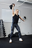 Blond woman lifting weights in gym\n