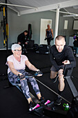 Coach assisting to senior woman exercising in gym\n