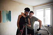 Smiling male homosexual couple standing together during apartment renovation\n