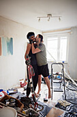 Smiling male homosexual kissing during apartment renovation\n