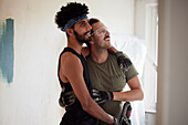 Smiling male homosexual couple standing together during apartment renovation\n