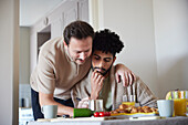Happy gay couple eating breakfast at home\n