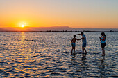 People enjoying sunset at Trabucador beach, Ebro Delta, Tarragona, Spain\n