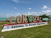 Ein 3-D-Schild für Corozal Town mit einer Maya-Maske in einem Park am Meer am Maya Beach in Corozal, Belize.