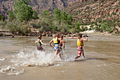 River guides running to jump in the water of the Green River on a rafting trip through Desolation Canyon in Utah.\n