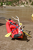 A duckie or inflatable kayak with an elk antler attached on the shore in Desolation Canyon, Utah.\n