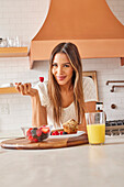 Portrait of smiling woman enjoying healthy breakfast in kitchen\n