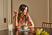 Lächelnde Frau genießt Salat am Tisch zu Hause