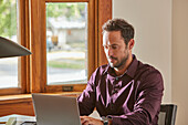 Man using laptop at desk at home\n