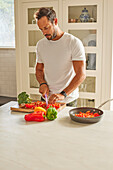 Man cutting vegetables in kitchen\n