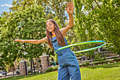 Lächelndes Mädchen (12-13) spielt mit Hula-Hoop-Reifen im Park