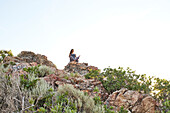 Mid adult woman meditating in mountains\n