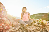Mid adult woman meditating in mountains\n