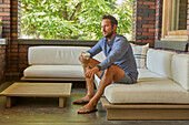 Mid adult man relaxing on sofa on patio\n