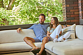 Mid adult couple relaxing on sofa on patio\n