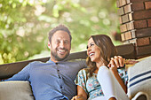 Mid adult couple relaxing on sofa on patio\n