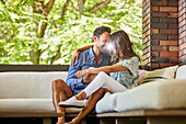 Mid adult couple relaxing on sofa on patio\n