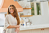 Portrait einer lächelnden jungen Frau in der Küche stehend