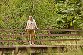 Reife Frau steht auf Brücke in der Natur