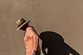 Senior woman in hat casting shadow on wall\n