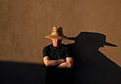 Älterer Mann mit Strohhut wirft Schatten auf Wand