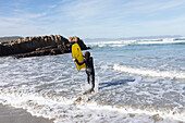 Südafrika, Hermanus, Junge (10-11) beim Einstieg in den Atlantik mit Bodyboard in Kammabaai Beach