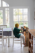 Boy (10-11) pretending to drive homemade steering wheel at home\n